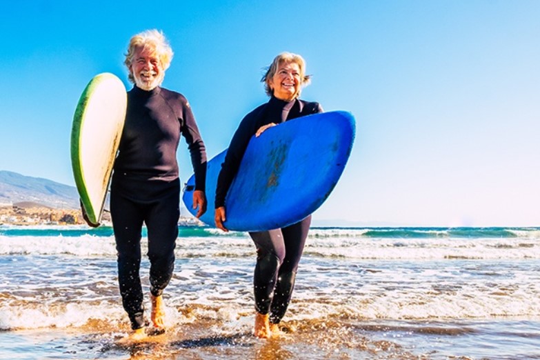 diabetes management. older women and men on beach with surf boards.