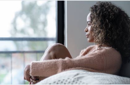 diabetes stress management. women looking on couch looking out window.